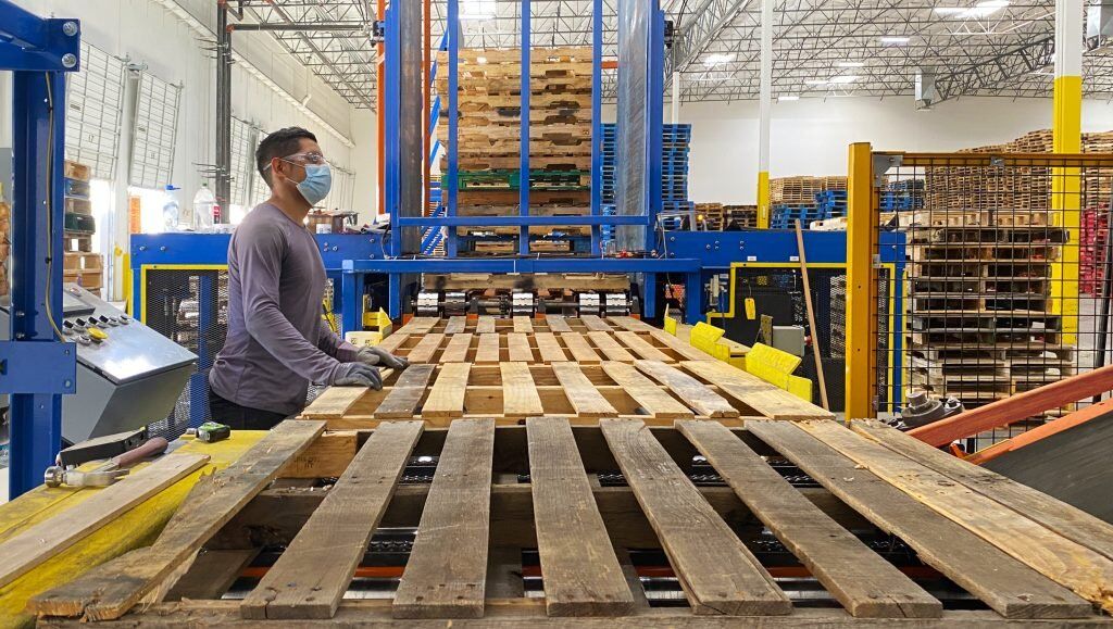 Pallet Broker LLC team member operating AMS pallet repair equipment